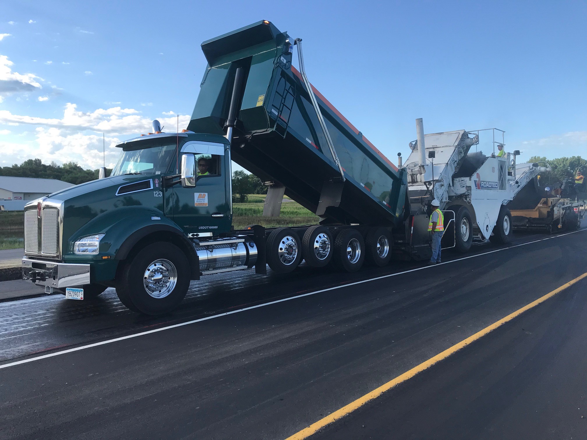 Two Trucks working to pave a road